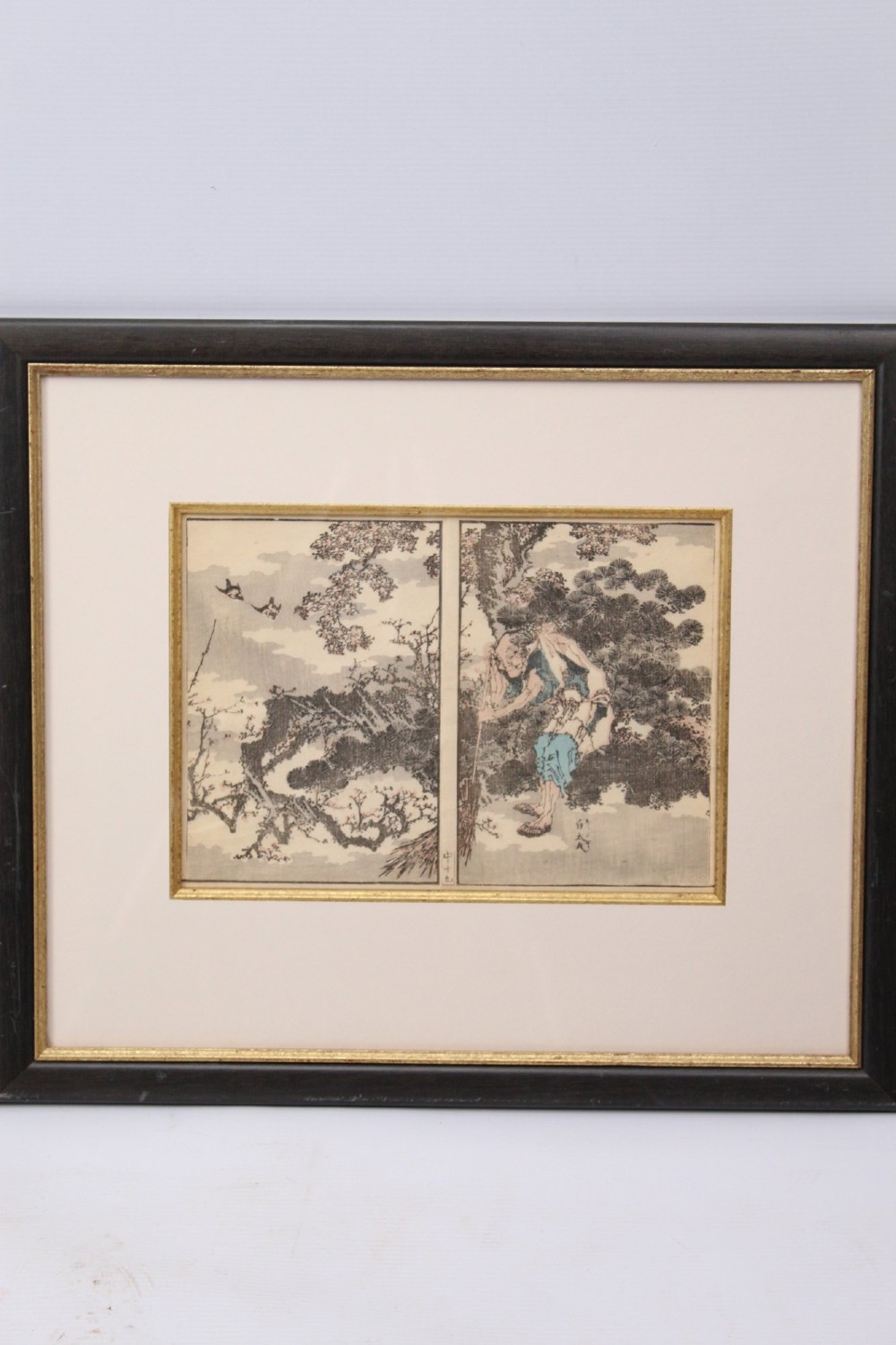 A pair of framed Japanese woodblock prints featuring detailed figurative and landscape illustrations mounted in cream mats within dark wooden frames. View IV