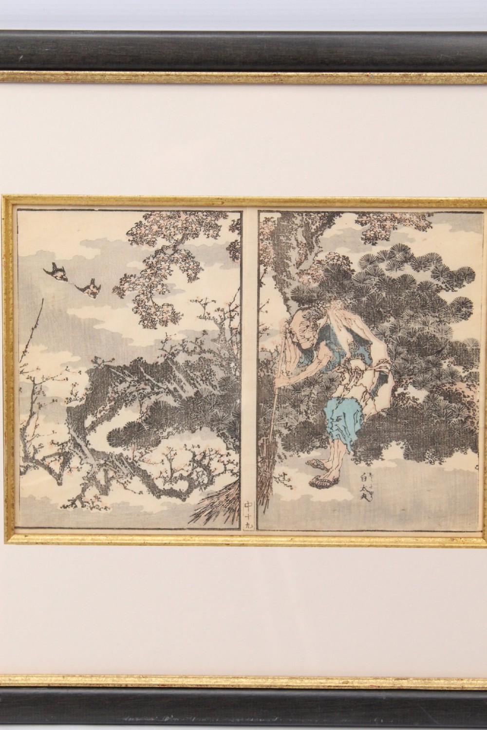 A pair of framed Japanese woodblock prints featuring detailed figurative and landscape illustrations mounted in cream mats within dark wooden frames. View V