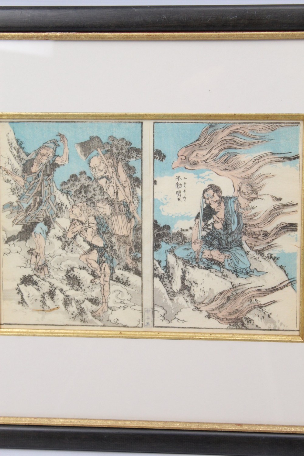A pair of framed Japanese woodblock prints featuring detailed figurative and landscape illustrations mounted in cream mats within dark wooden frames. View VI