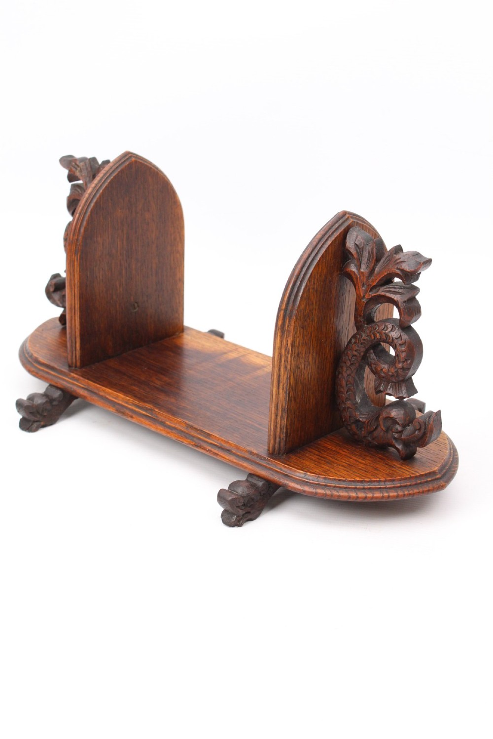 A dark oak desktop book stand featuring pointed arch uprights, carved mythical creature side accents, and scroll feet. View III