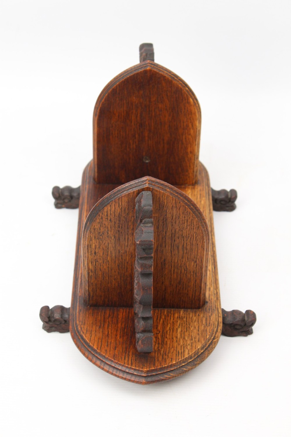 A dark oak desktop book stand featuring pointed arch uprights, carved mythical creature side accents, and scroll feet. View IV