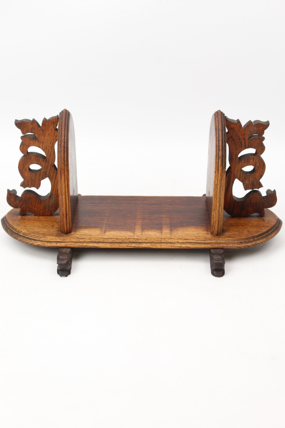 A dark oak desktop book stand featuring pointed arch uprights, carved mythical creature side accents, and scroll feet. View V