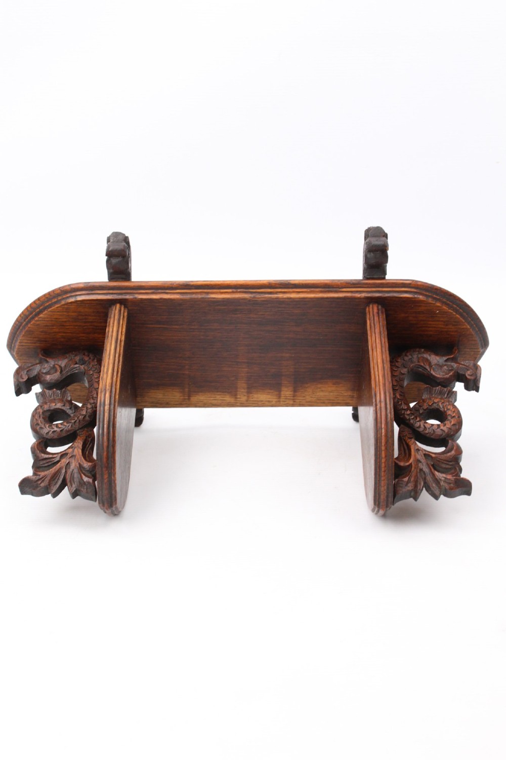 A dark oak desktop book stand featuring pointed arch uprights, carved mythical creature side accents, and scroll feet. View VI