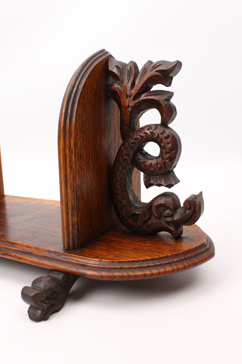 A dark oak desktop book stand featuring pointed arch uprights, carved mythical creature side accents, and scroll feet. View IX
