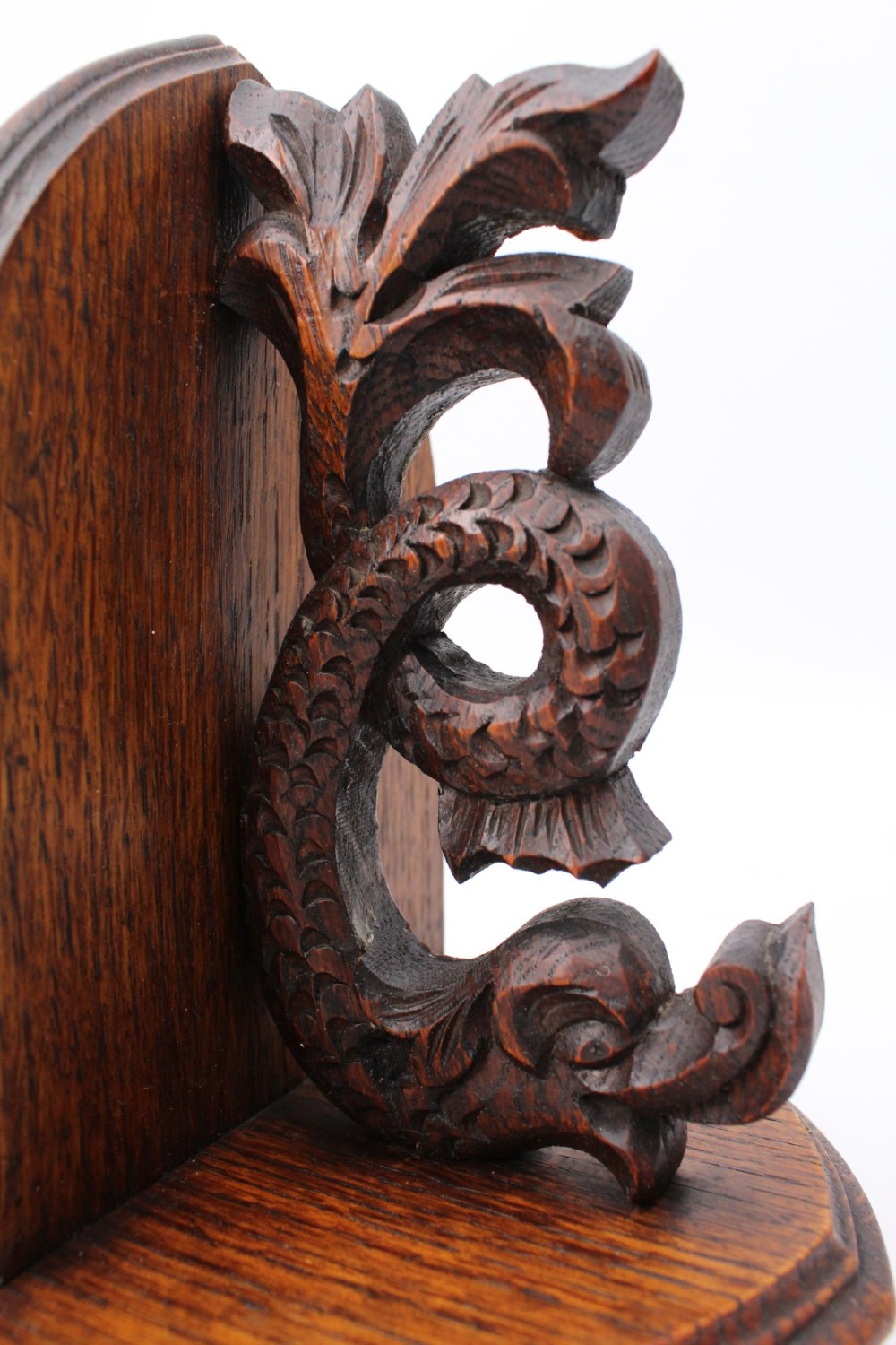 A dark oak desktop book stand featuring pointed arch uprights, carved mythical creature side accents, and scroll feet. View X