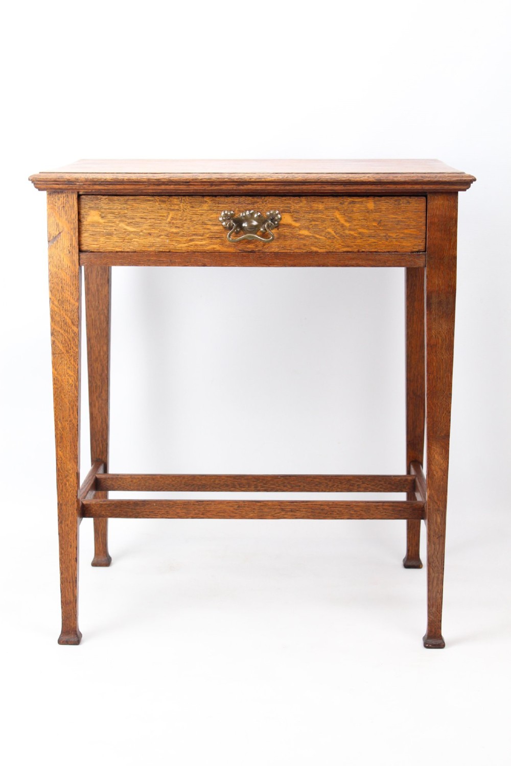 A compact Arts and Crafts oak writing desk featuring a single drawer with a brass drop handle, straight square legs, and lower stretchers. View II