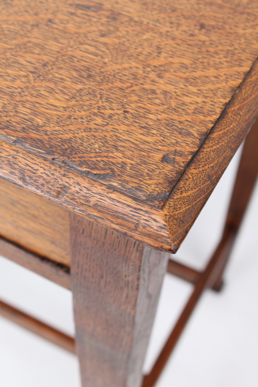 A compact Arts and Crafts oak writing desk featuring a single drawer with a brass drop handle, straight square legs, and lower stretchers. View IX