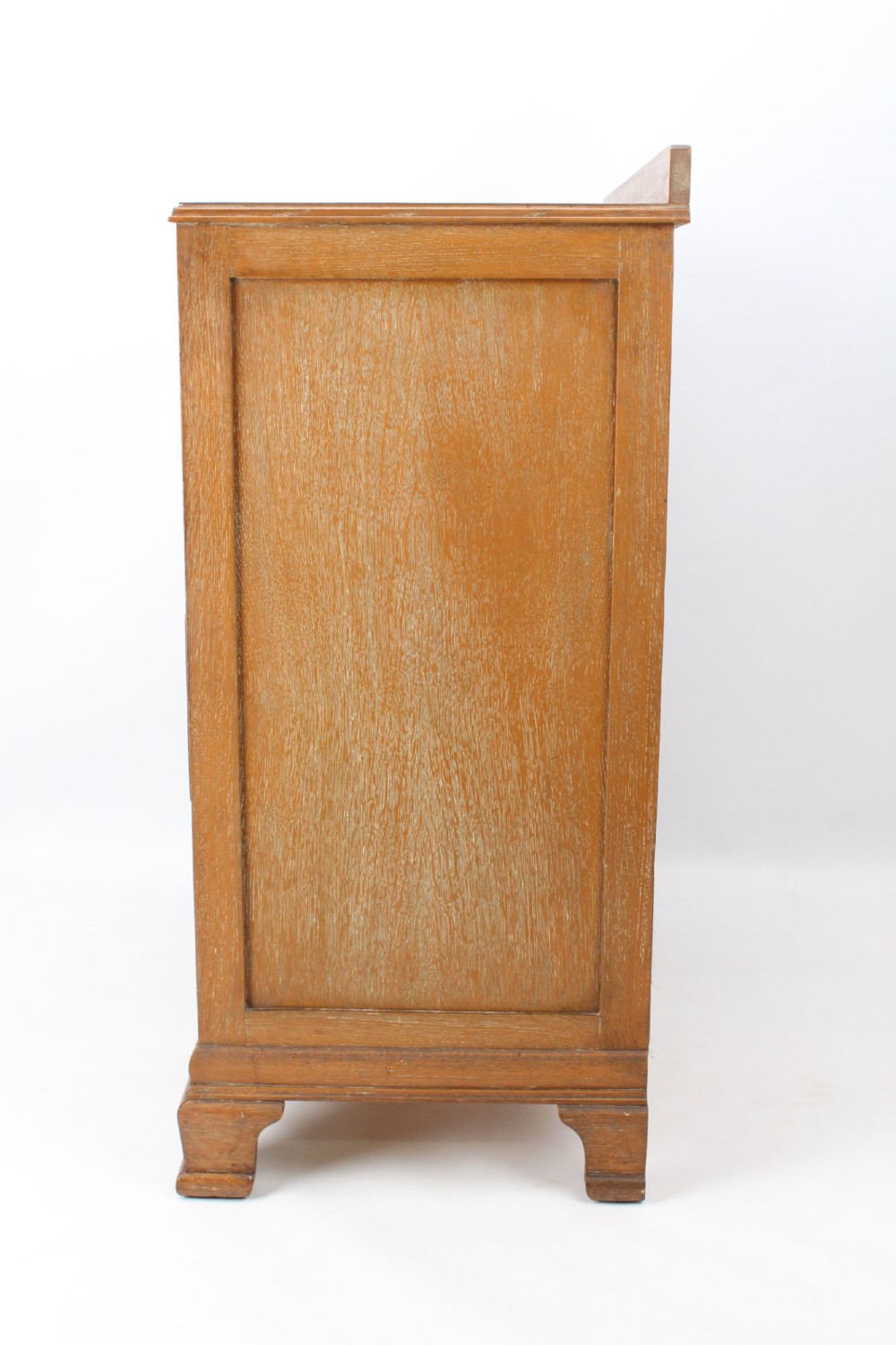 A light oak Art Deco chest of drawers featuring four drawers with textured metal handles, a low gallery back, and bracket feet. View V