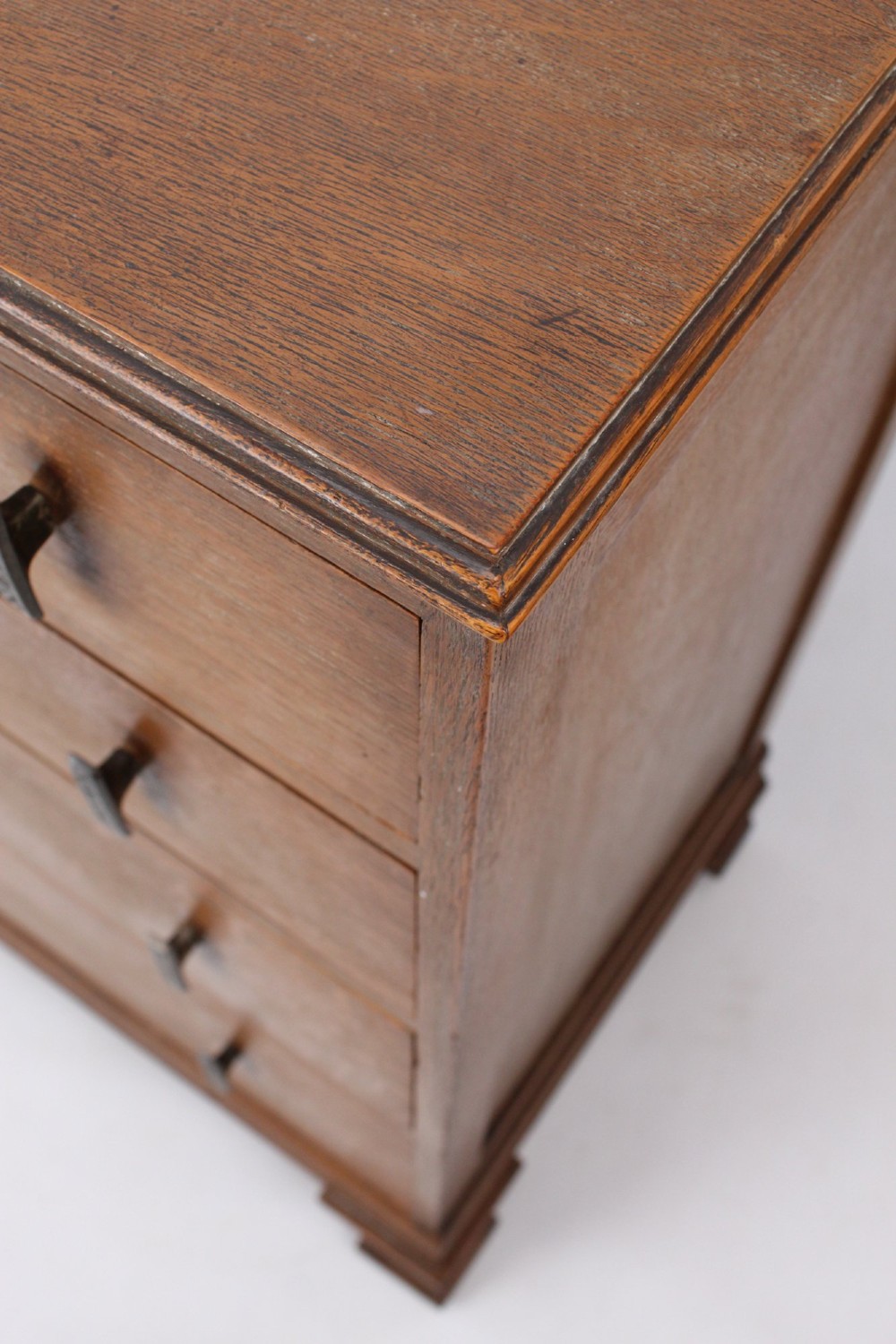 A light oak Art Deco chest of drawers featuring four drawers with textured metal handles, a low gallery back, and bracket feet. View IX