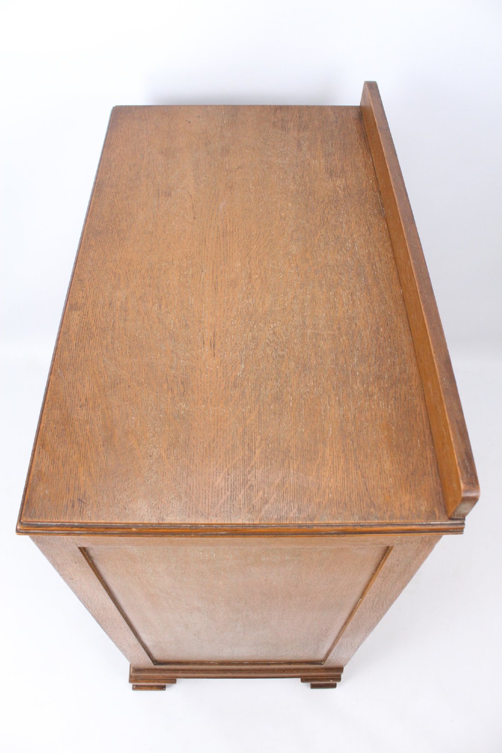 A light oak Art Deco chest of drawers featuring four drawers with textured metal handles, a low gallery back, and bracket feet. View XIII