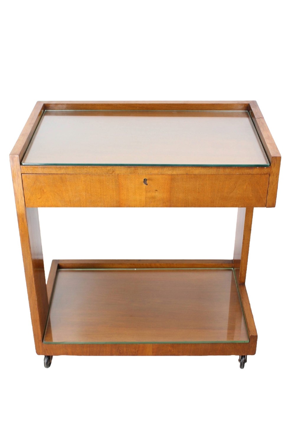 An Art Deco warm brown walnut two-tier trolley featuring inset glass tops, a drawer with a brass keyhole, and concealed castors. View II