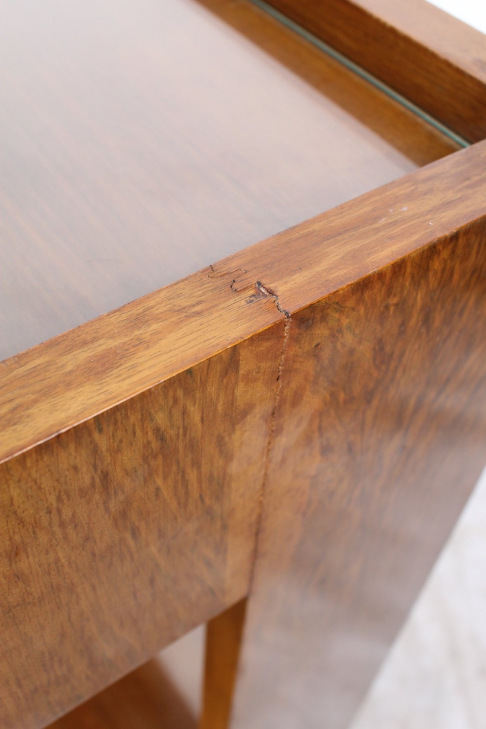 An Art Deco warm brown walnut two-tier trolley featuring inset glass tops, a drawer with a brass keyhole, and concealed castors. View X