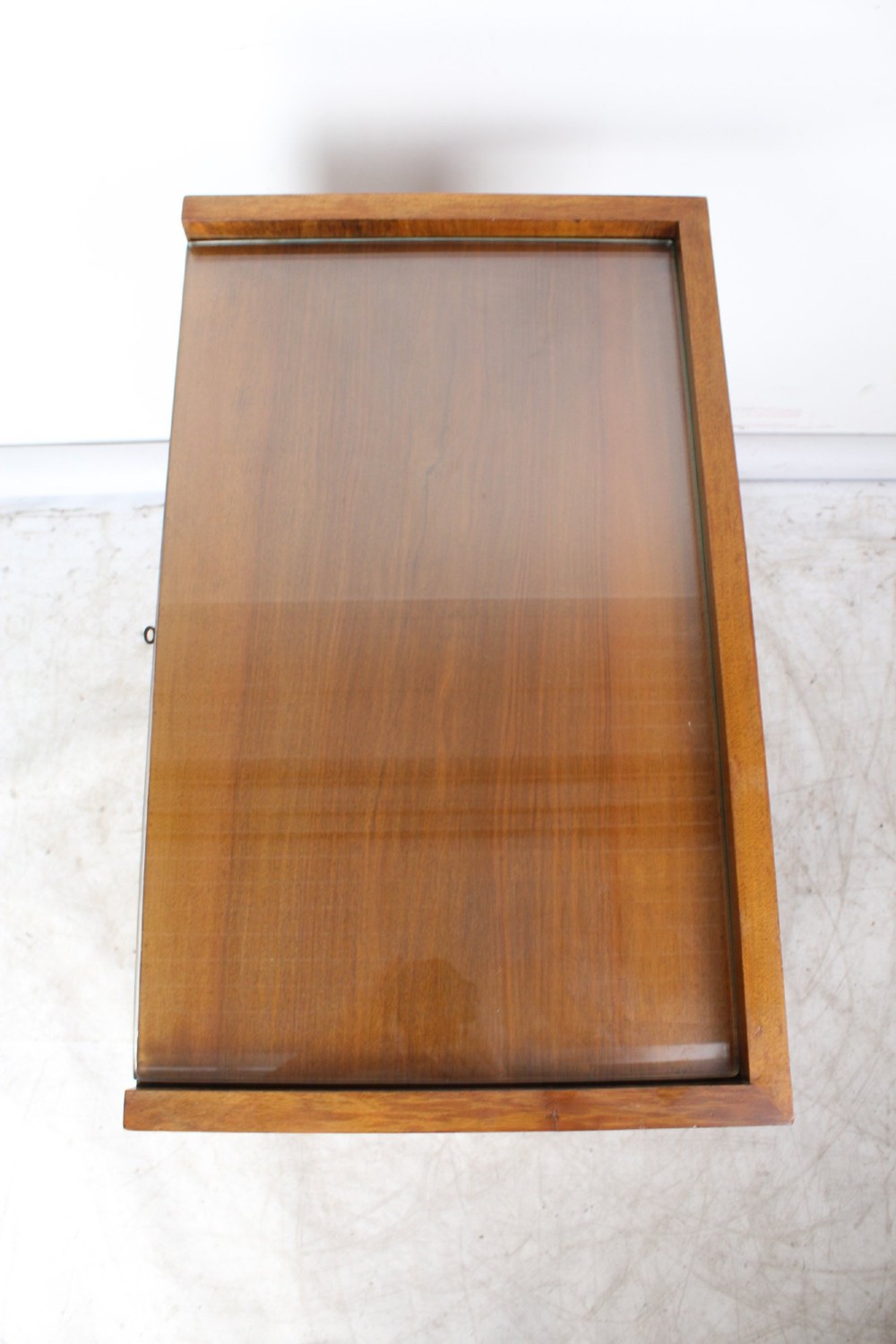 An Art Deco warm brown walnut two-tier trolley featuring inset glass tops, a drawer with a brass keyhole, and concealed castors. View XI