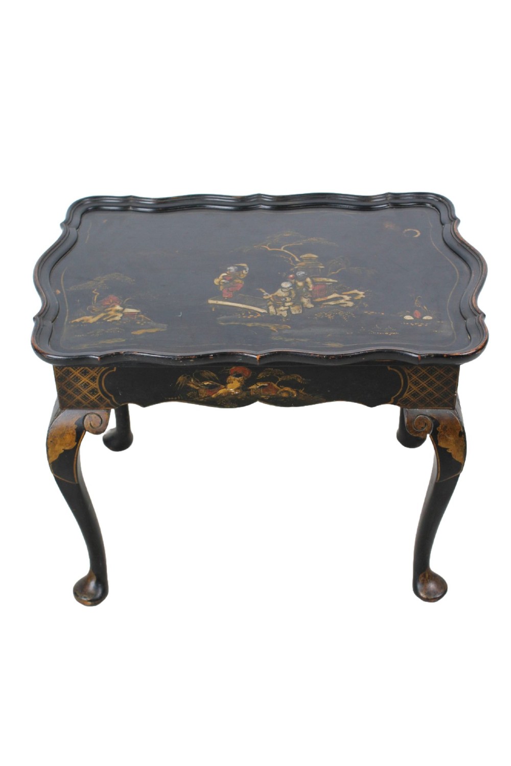 A low black lacquered Edwardian coffee table featuring gilded Chinoiserie figures, a serpentine tray-top edge, and cabriole legs.
