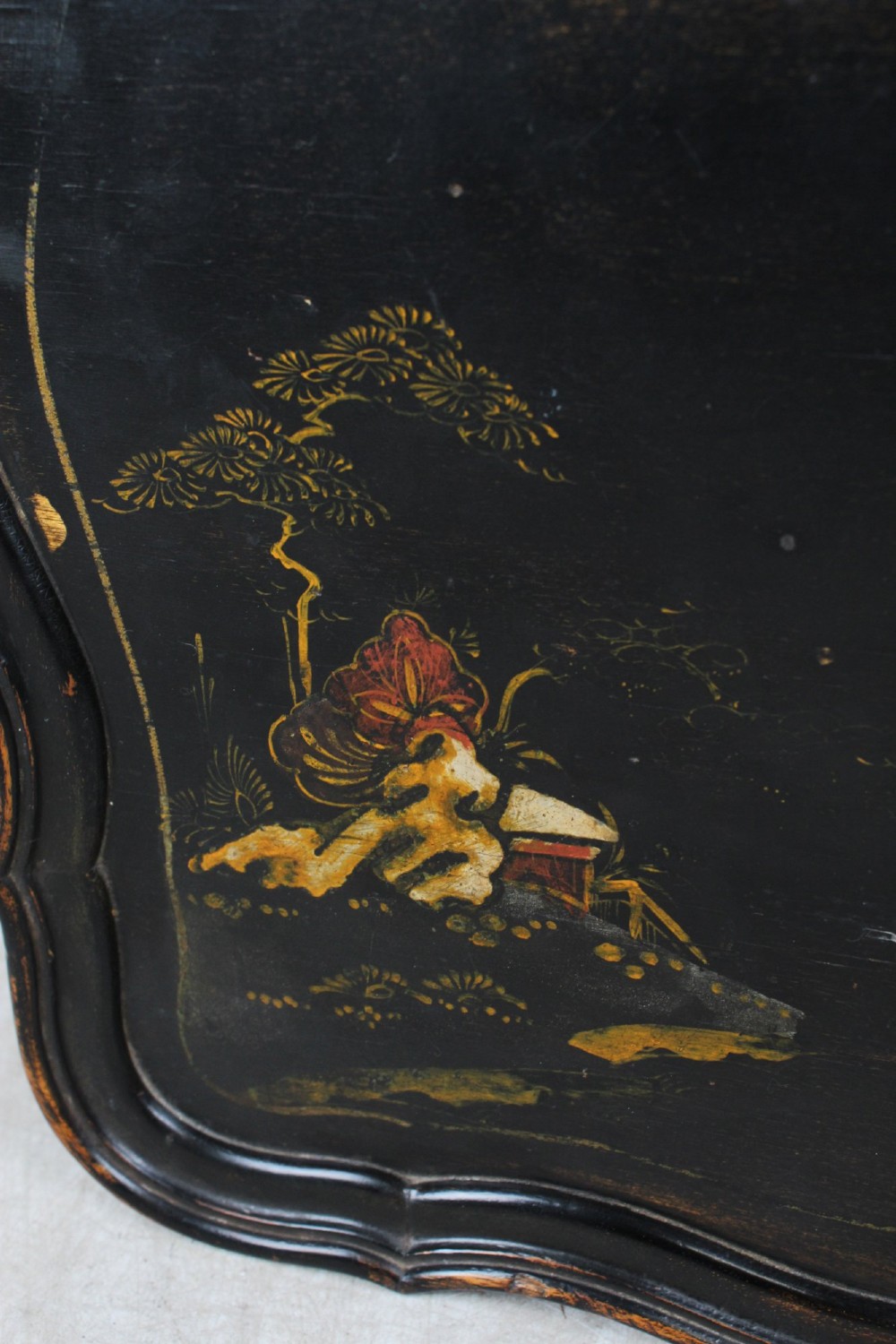 A low black lacquered Edwardian coffee table featuring gilded Chinoiserie figures, a serpentine tray-top edge, and cabriole legs. View IX