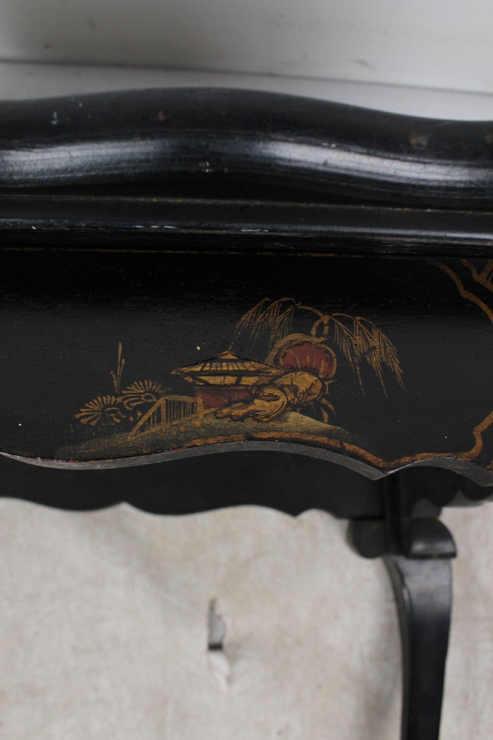 A low black lacquered Edwardian coffee table featuring gilded Chinoiserie figures, a serpentine tray-top edge, and cabriole legs. View XII