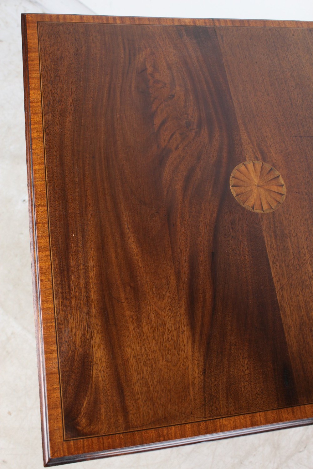 An Edwardian mahogany square side table featuring a central inlaid sunburst medallion, crossbanded border, and a lower undertier shelf with a pierced gallery. View VIII
