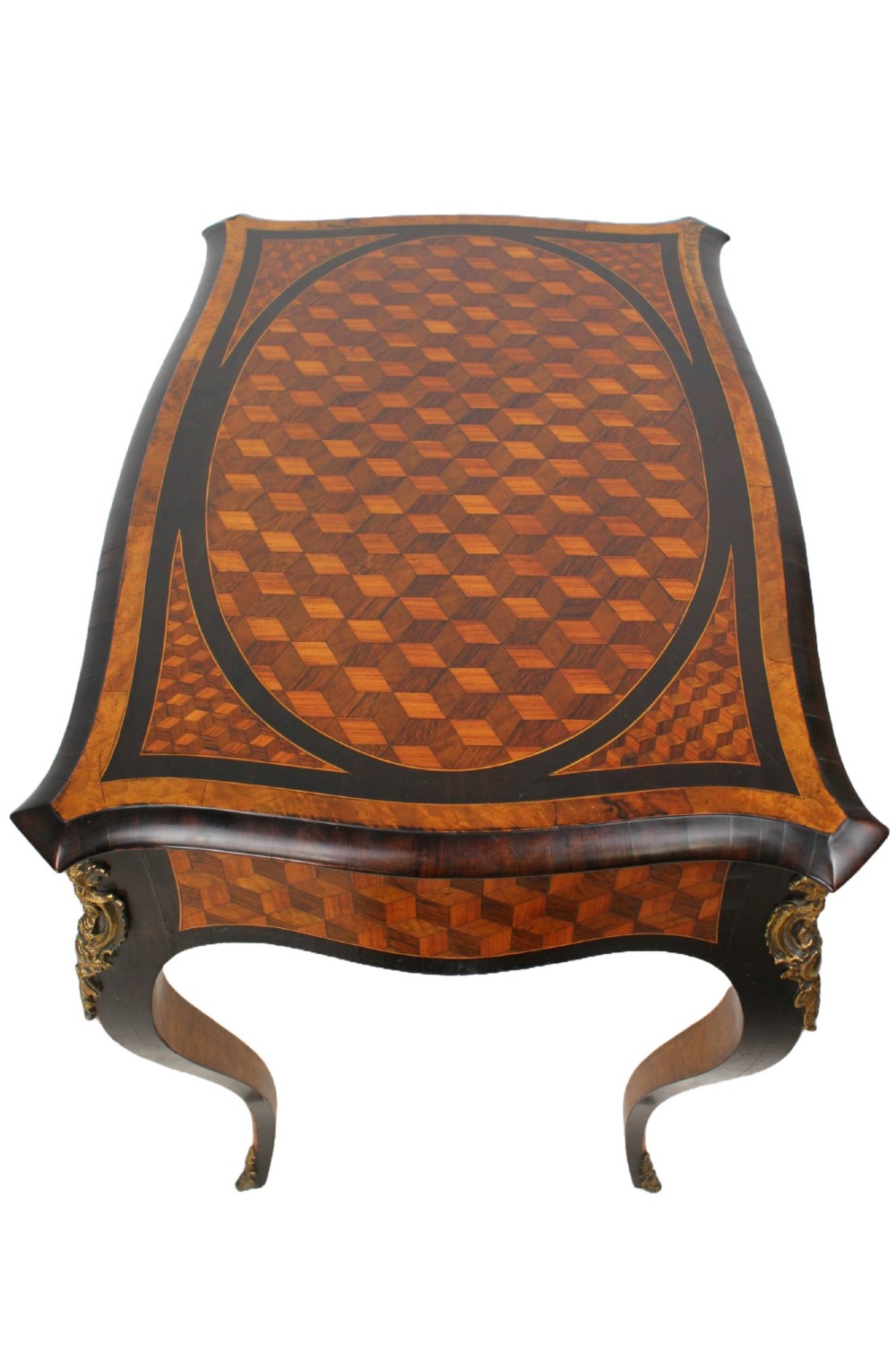 A Victorian Louis XV Revival writing table featuring geometric cube parquetry inlay, serpentine edges, ebonised borders, cabriole legs, and gold-toned bronze mounts. View IV