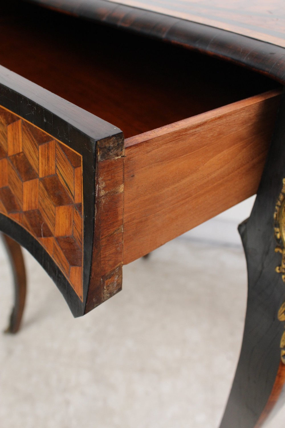 A Victorian Louis XV Revival writing table featuring geometric cube parquetry inlay, serpentine edges, ebonised borders, cabriole legs, and gold-toned bronze mounts. View VIII