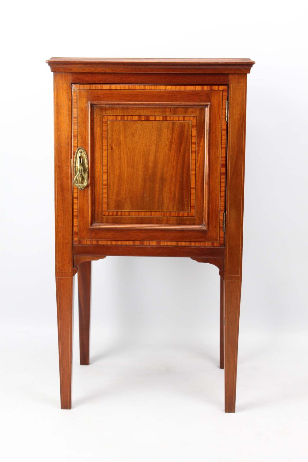 An Edwardian mahogany bedside cabinet featuring satinwood stringing inlay, a single panelled door with a brass handle, and square tapered legs.
