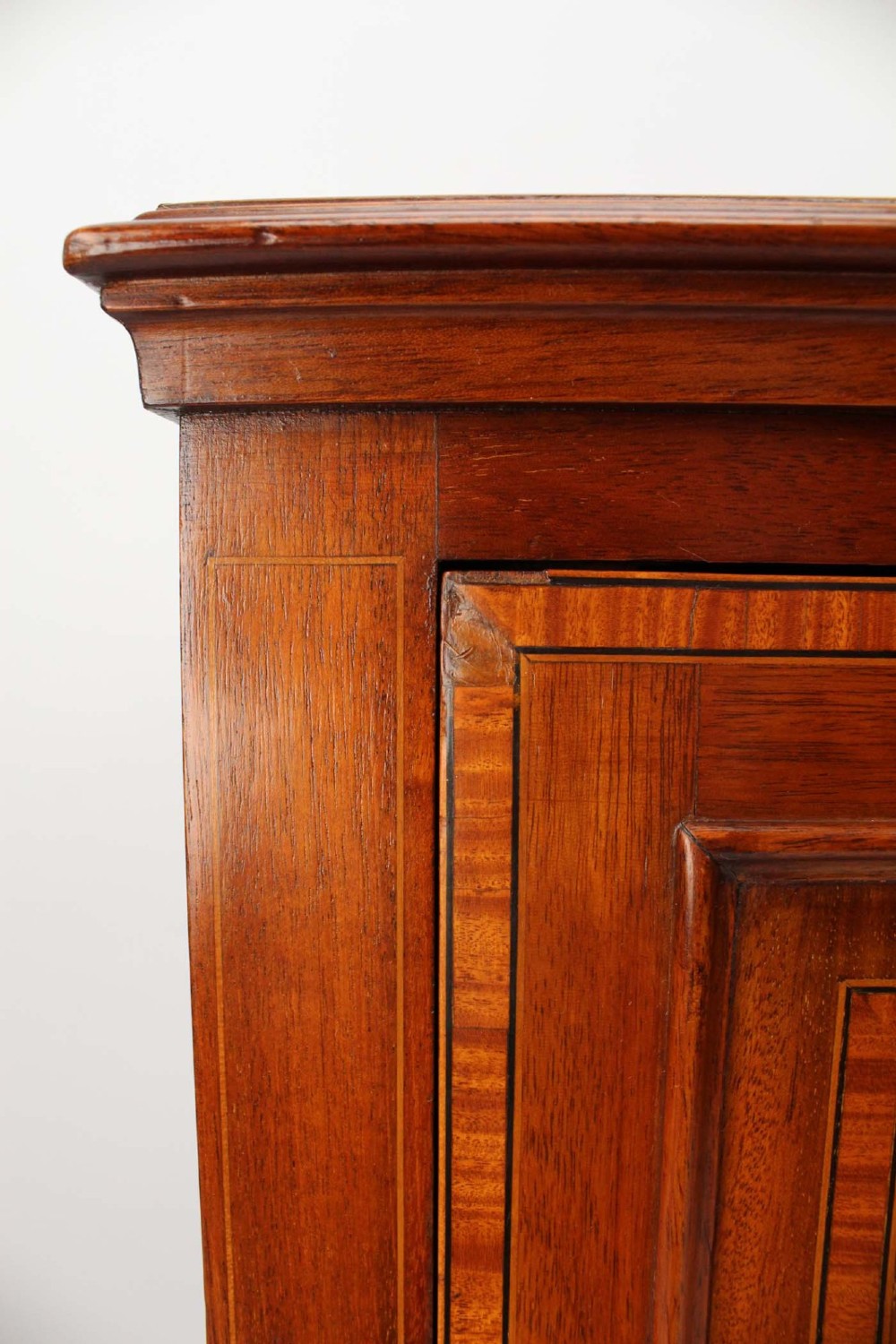 An Edwardian mahogany bedside cabinet featuring satinwood stringing inlay, a single panelled door with a brass handle, and square tapered legs. View IX