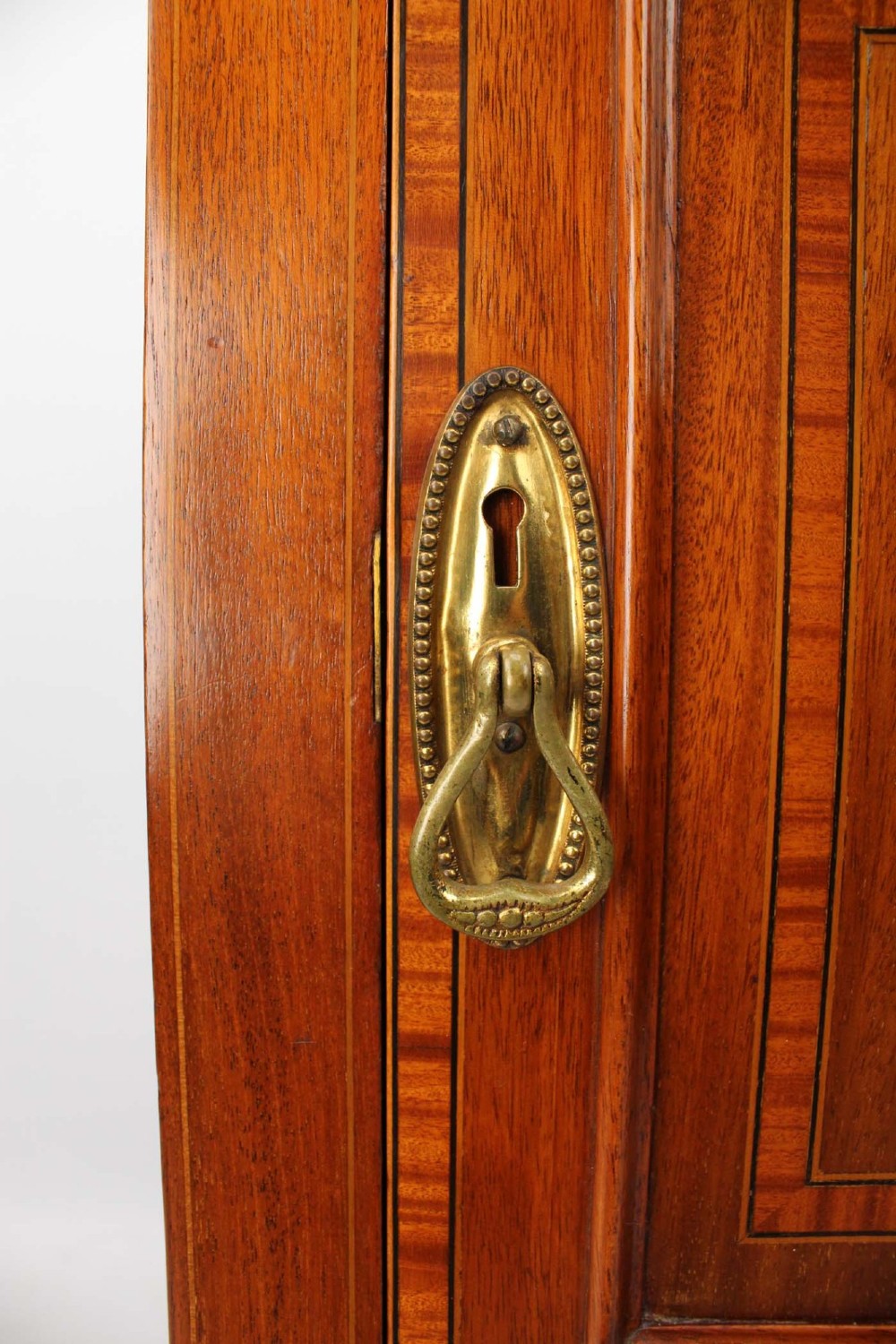 An Edwardian mahogany bedside cabinet featuring satinwood stringing inlay, a single panelled door with a brass handle, and square tapered legs. View X