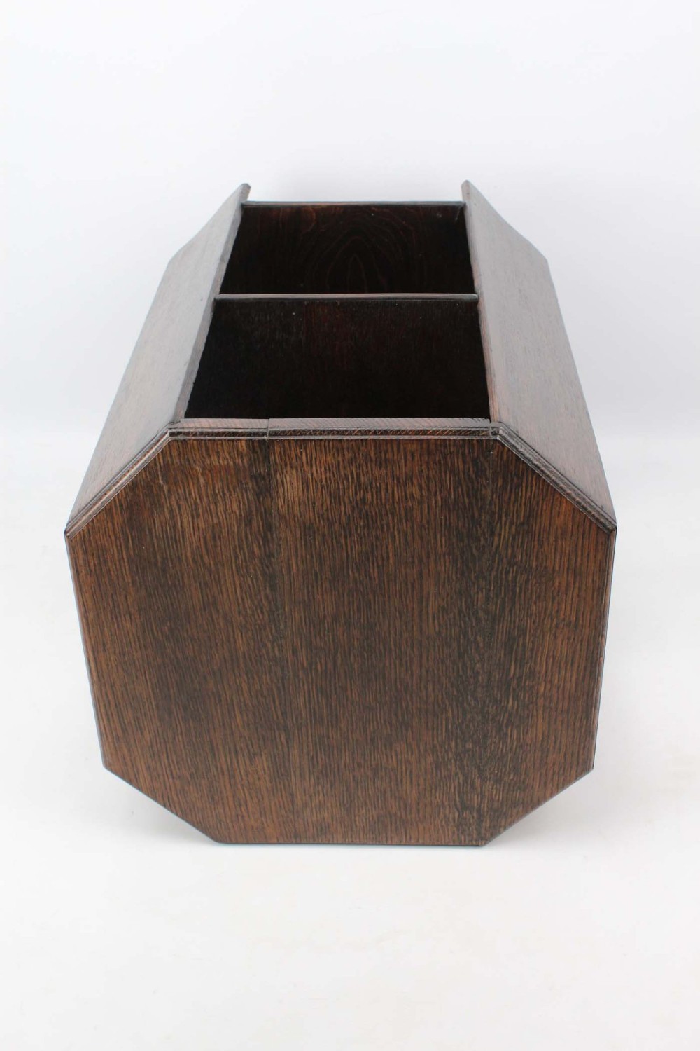 An octagonal dark oak Art Deco style book table featuring three vertical side panels and two open lower shelves. View IV