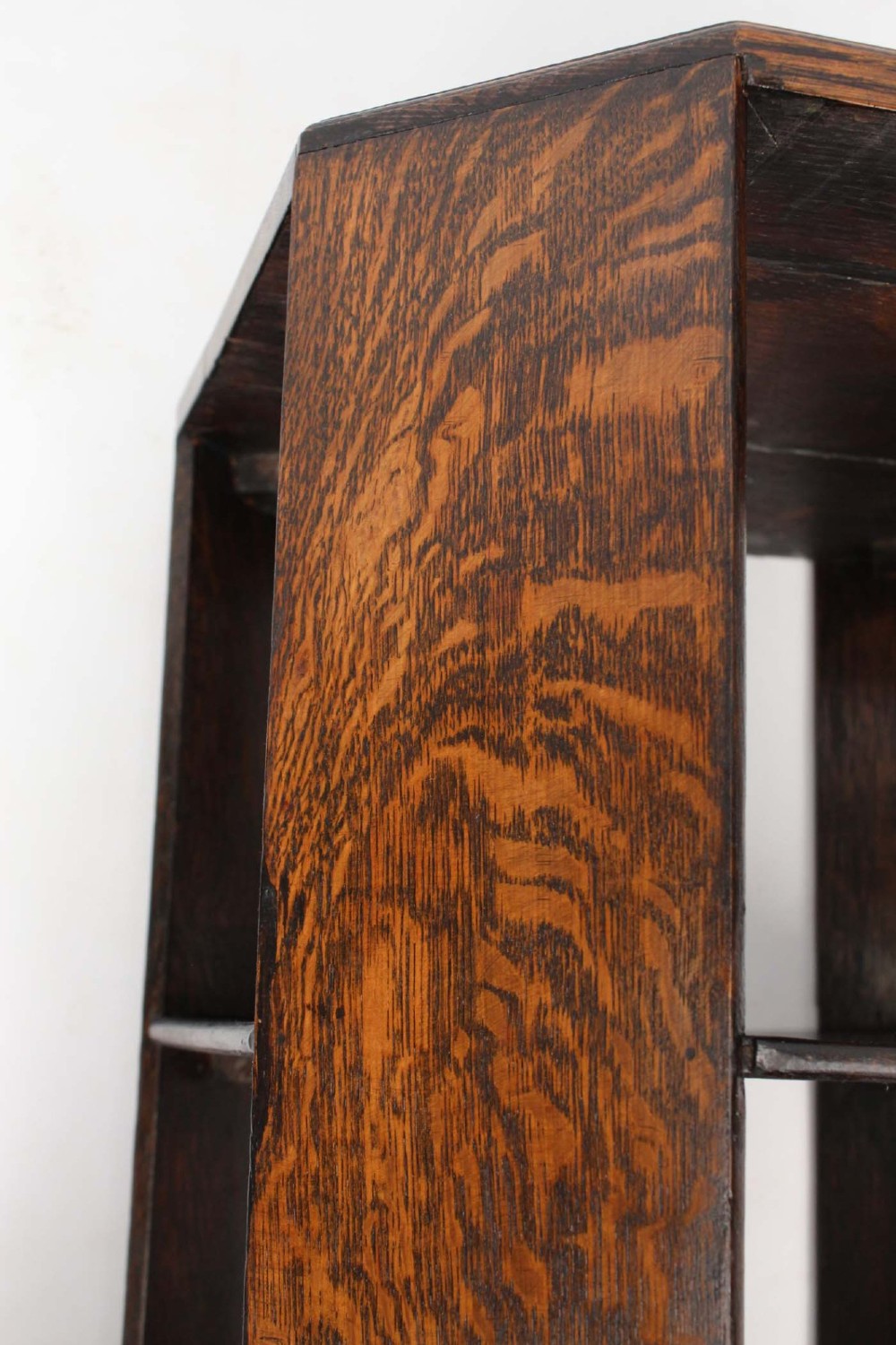 An octagonal dark oak Art Deco style book table featuring three vertical side panels and two open lower shelves. View VII