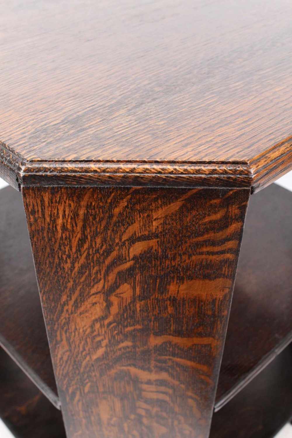 An octagonal dark oak Art Deco style book table featuring three vertical side panels and two open lower shelves. View VIII