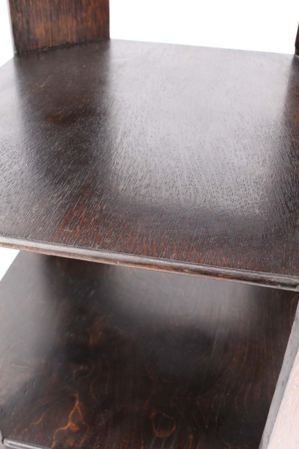 An octagonal dark oak Art Deco style book table featuring three vertical side panels and two open lower shelves. View X