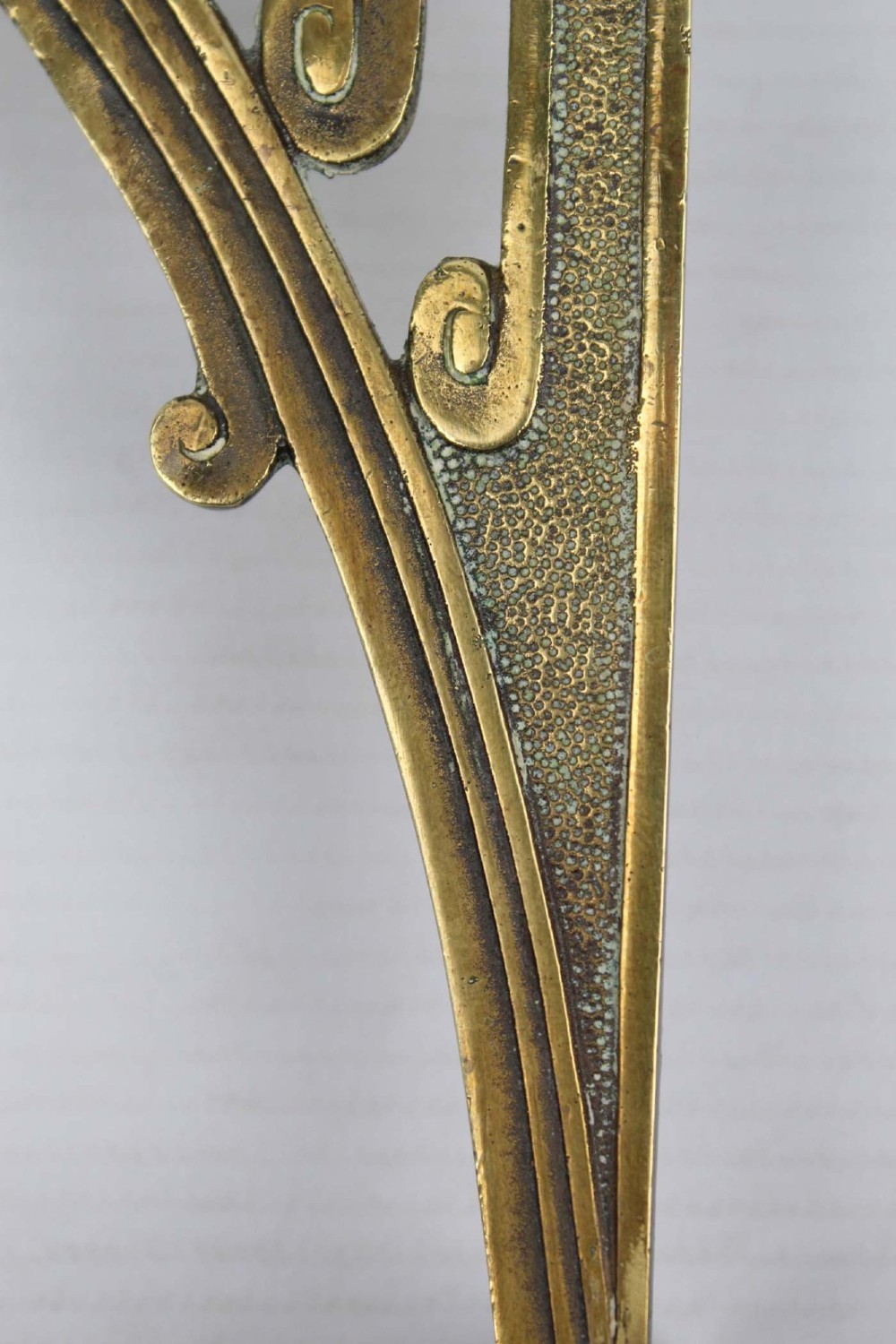 A stylized cast brass Art Deco wall hanging bracket featuring openwork scroll details and a lower swivel hook. View VII