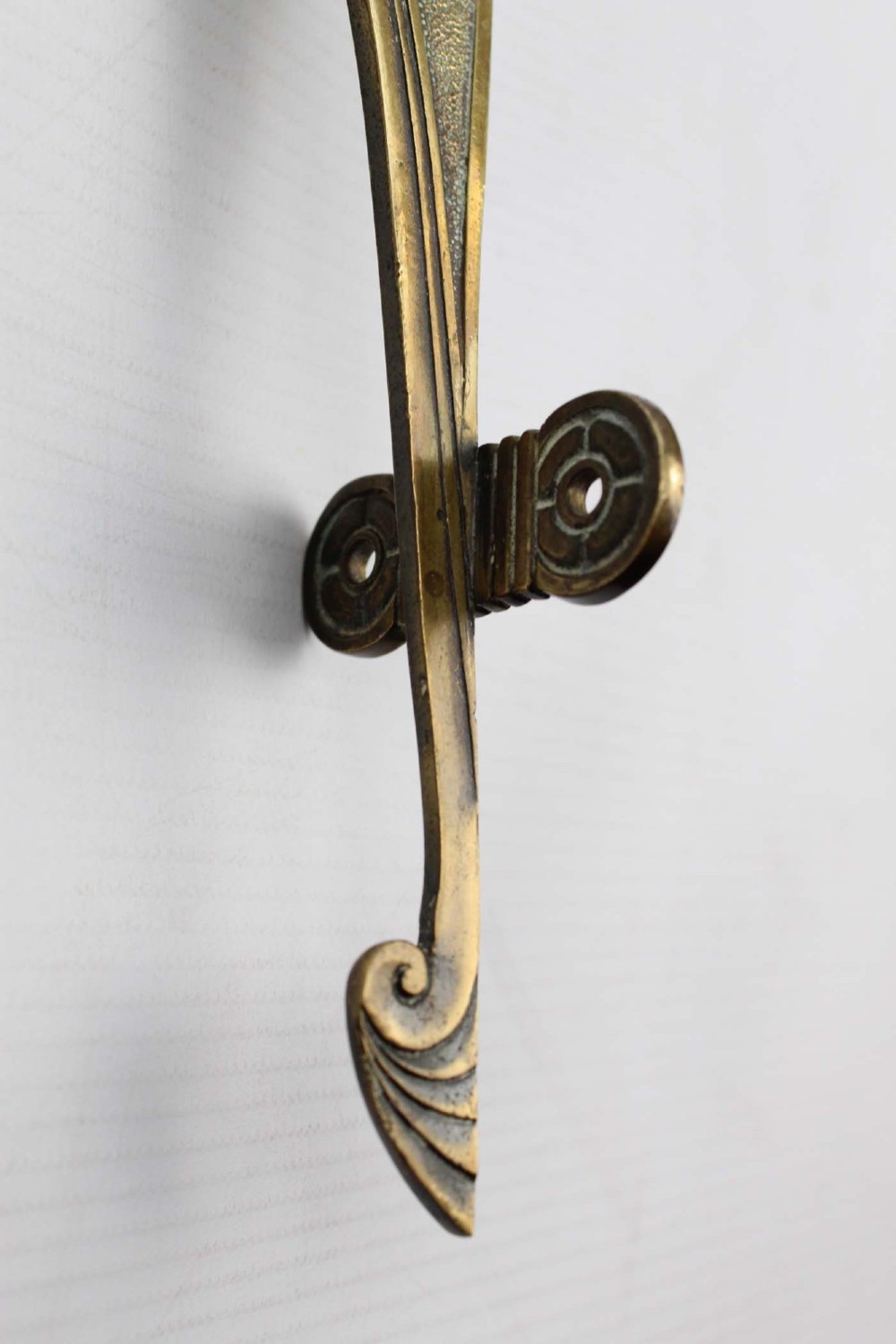 A stylized cast brass Art Deco wall hanging bracket featuring openwork scroll details and a lower swivel hook. View XII