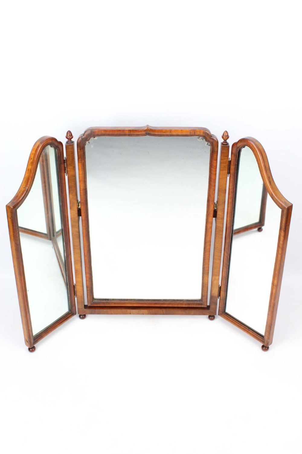 A three-panel walnut triptych dressing table mirror featuring arched side wings, turned finials, and brass hinges.