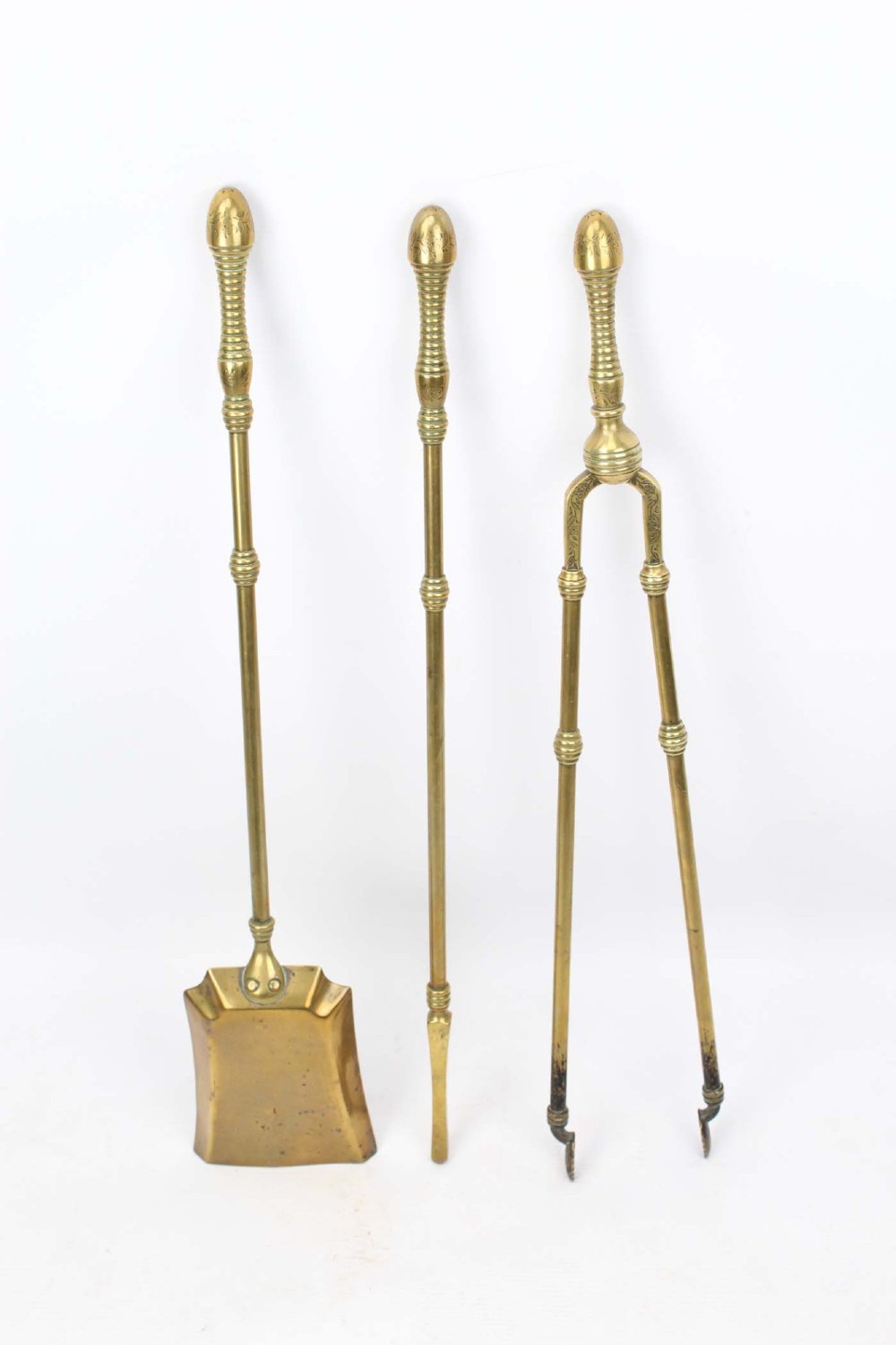 A three-piece set of Victorian brass fire tools consisting of a shovel, a poker, and tongs with turned and engraved handles. View XII