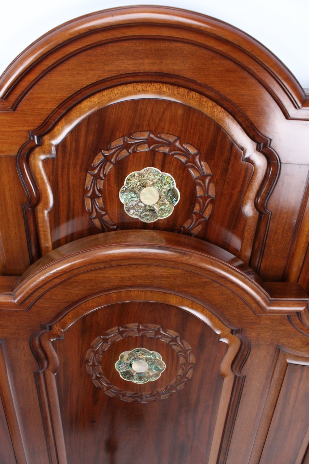 A Victorian walnut single bedstead featuring arched panels, carved circular wreaths, and central mother-of-pearl and abalone shell floral inlays. View V