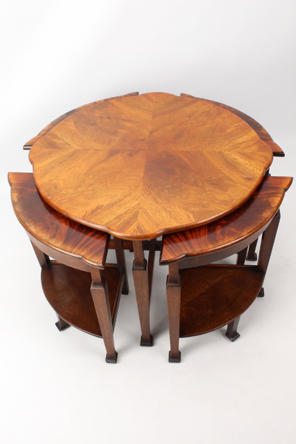 An Art Deco warm brown walnut circular coffee table featuring four sector-shaped nesting side tables stowed underneath. View II