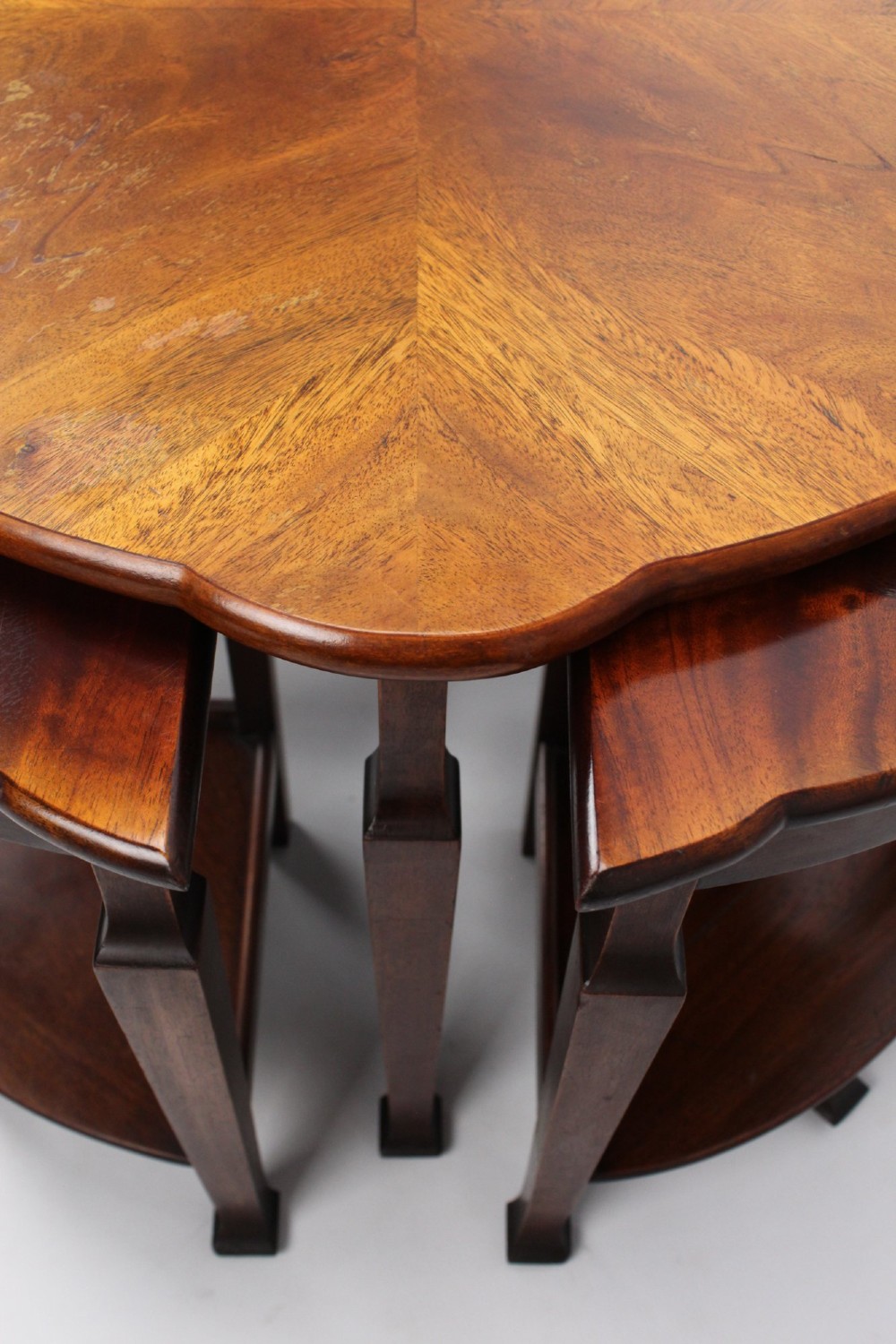 An Art Deco warm brown walnut circular coffee table featuring four sector-shaped nesting side tables stowed underneath. View VI