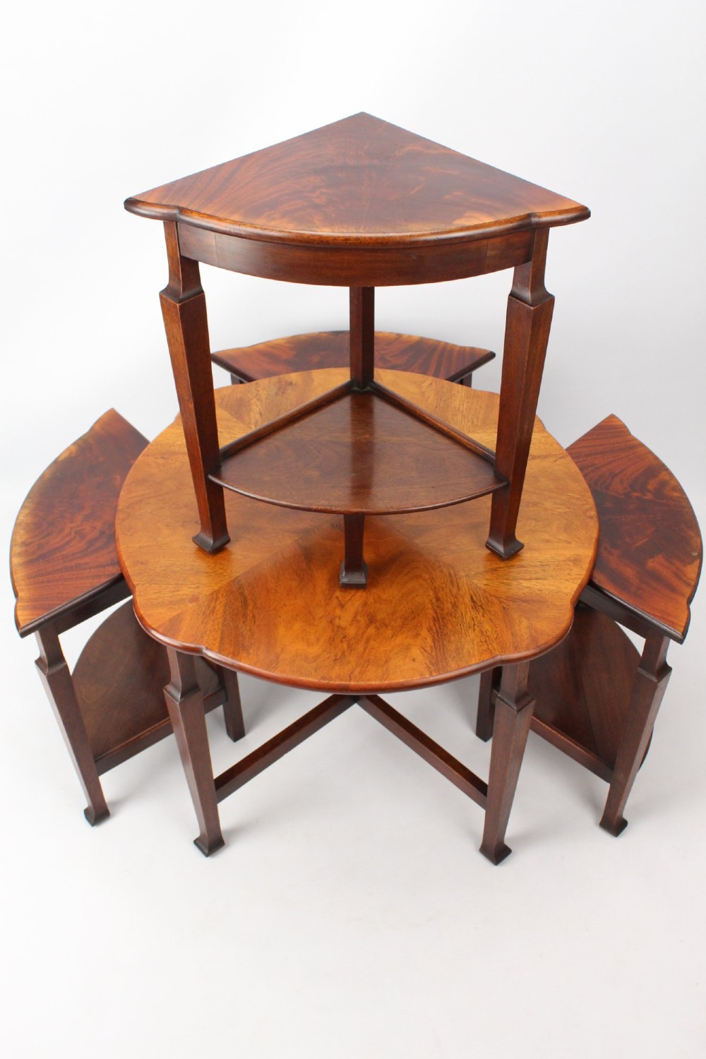 An Art Deco warm brown walnut circular coffee table featuring four sector-shaped nesting side tables stowed underneath. View VII