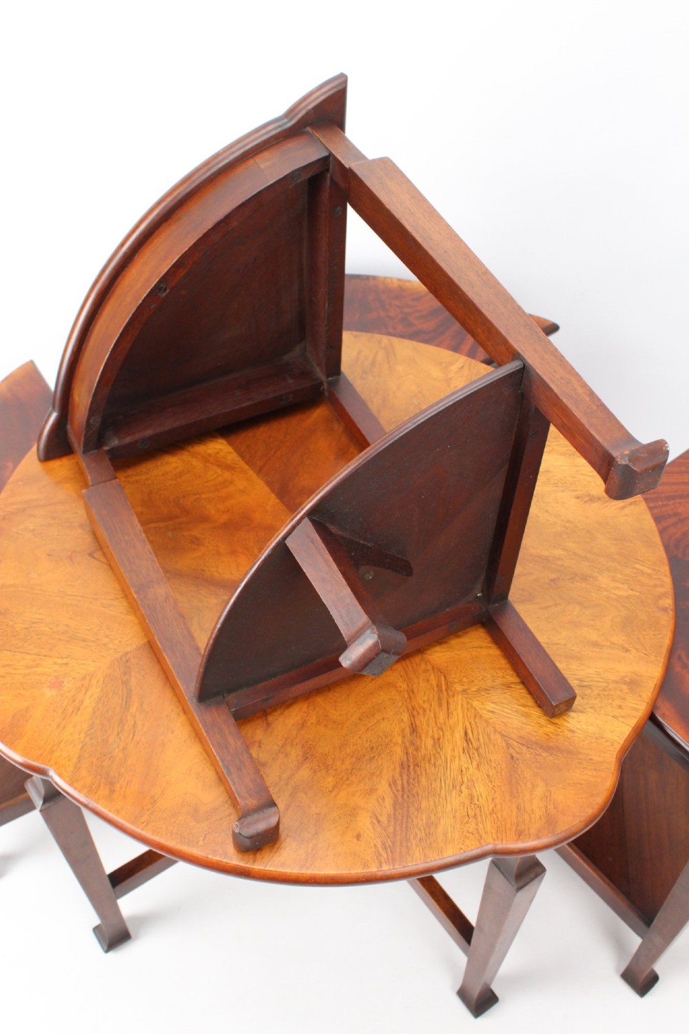 An Art Deco warm brown walnut circular coffee table featuring four sector-shaped nesting side tables stowed underneath. View IX