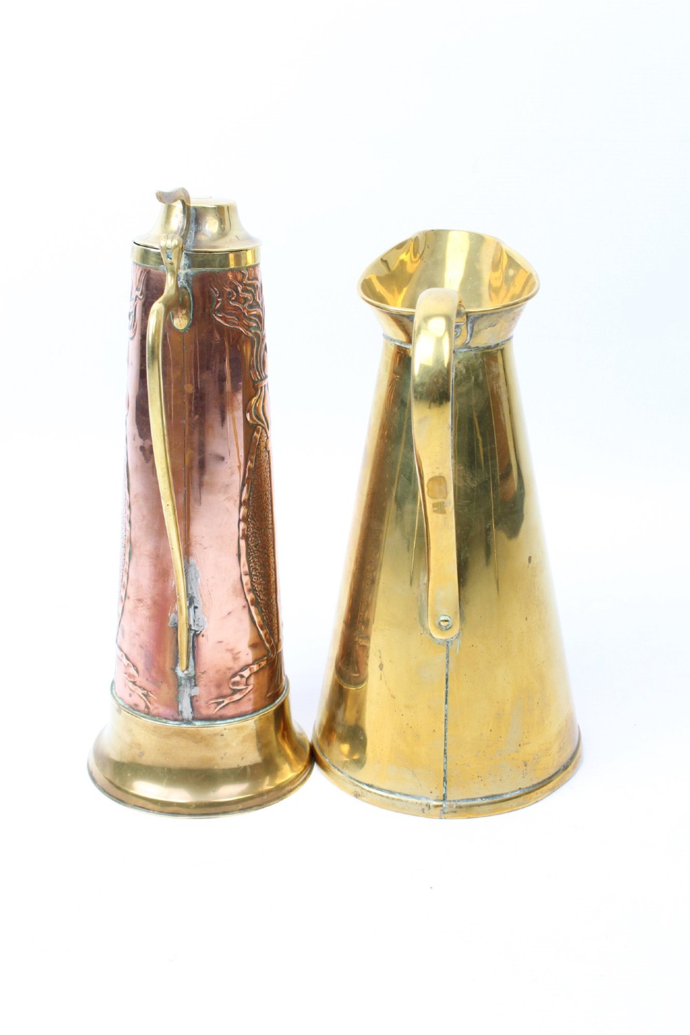 A pair of antique metal jugs, one crafted from repousse copper with brass fittings and a hinged lid alongside a tapered solid brass pitcher. View II