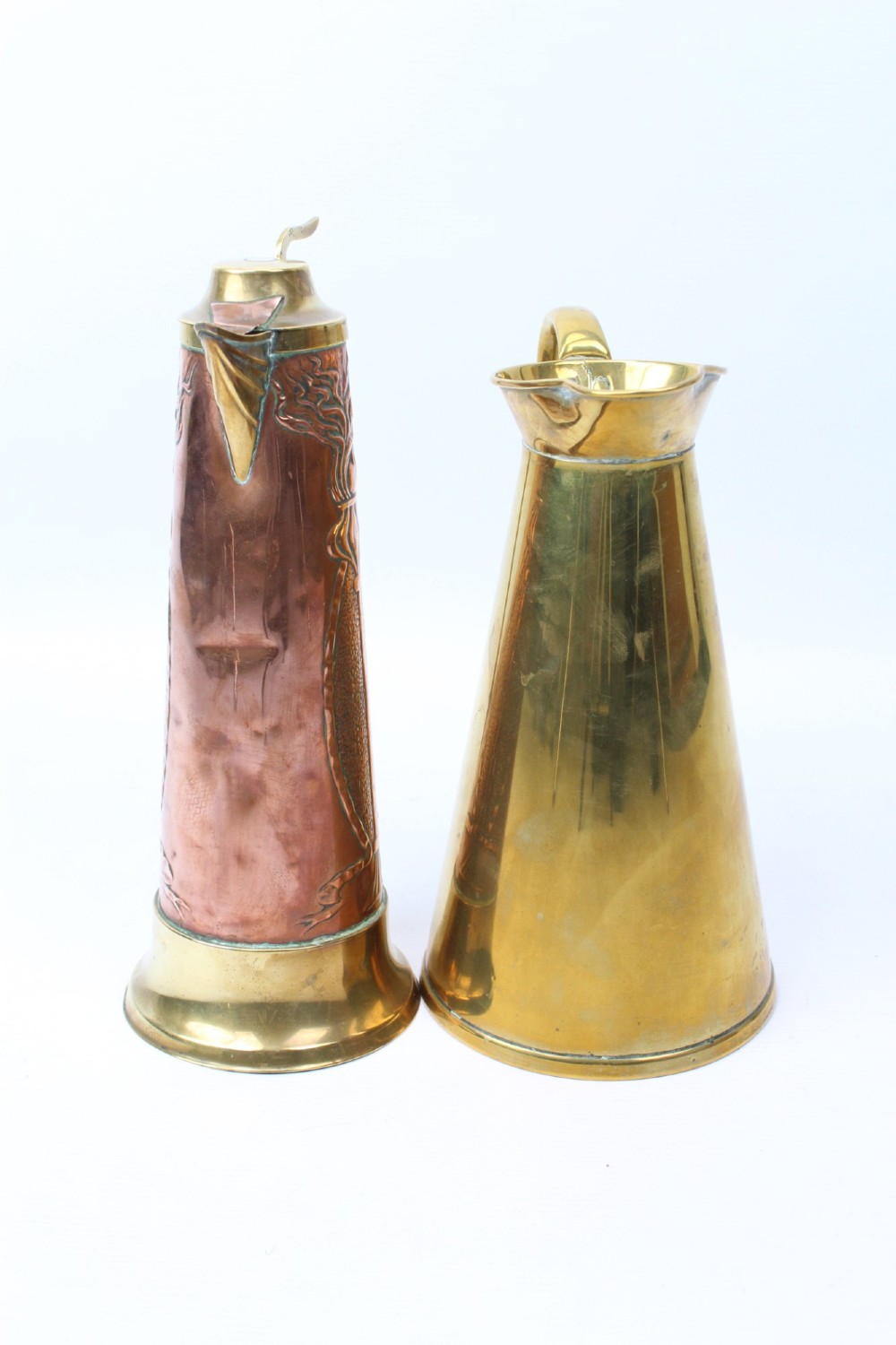 A pair of antique metal jugs, one crafted from repousse copper with brass fittings and a hinged lid alongside a tapered solid brass pitcher. View III