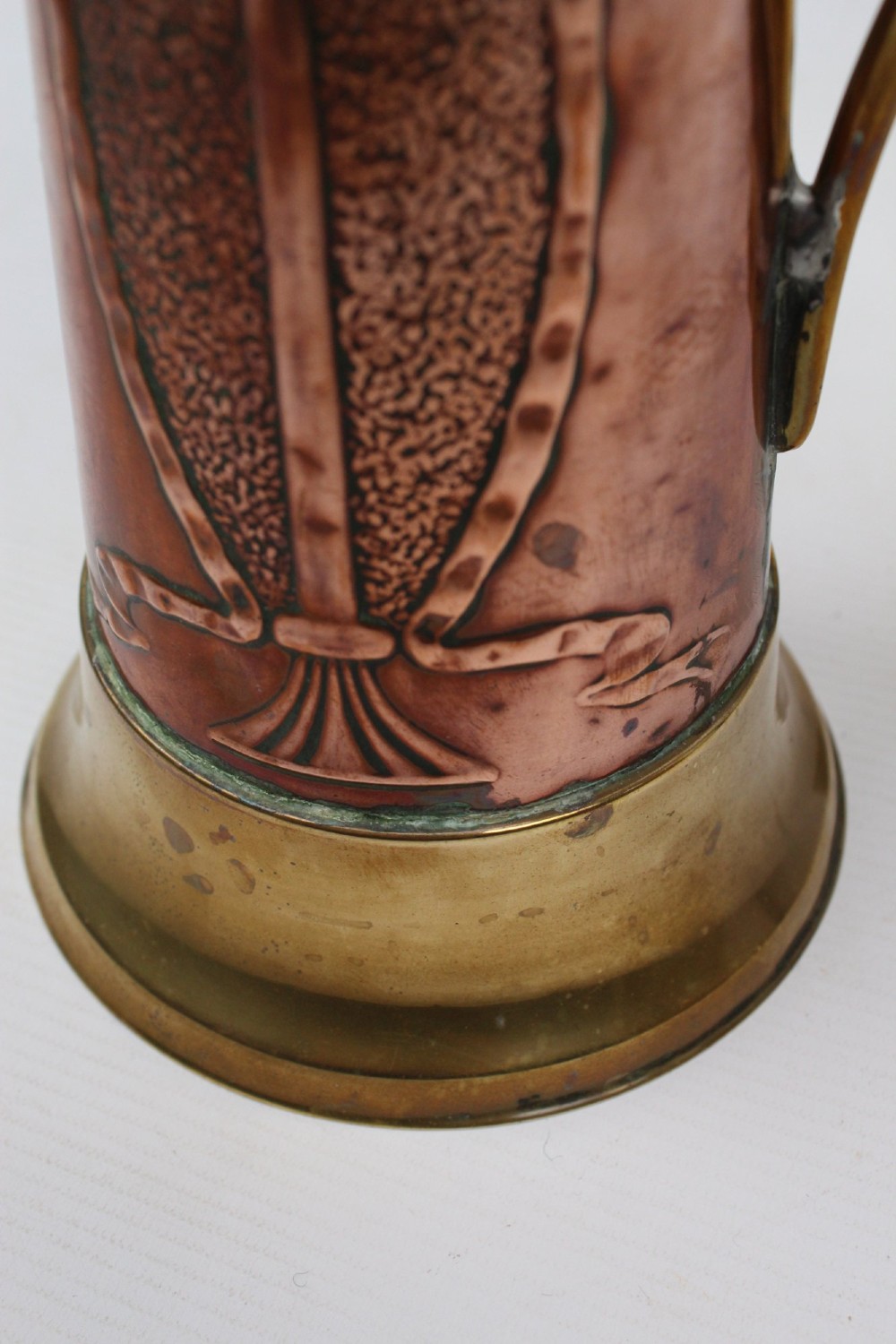 A pair of antique metal jugs, one crafted from repousse copper with brass fittings and a hinged lid alongside a tapered solid brass pitcher. View VIII