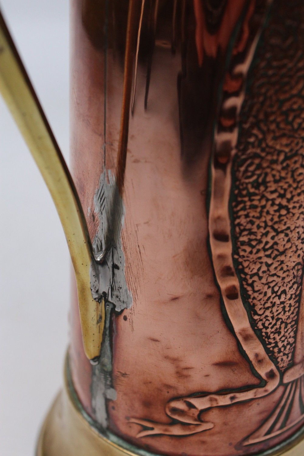 A pair of antique metal jugs, one crafted from repousse copper with brass fittings and a hinged lid alongside a tapered solid brass pitcher. View XI