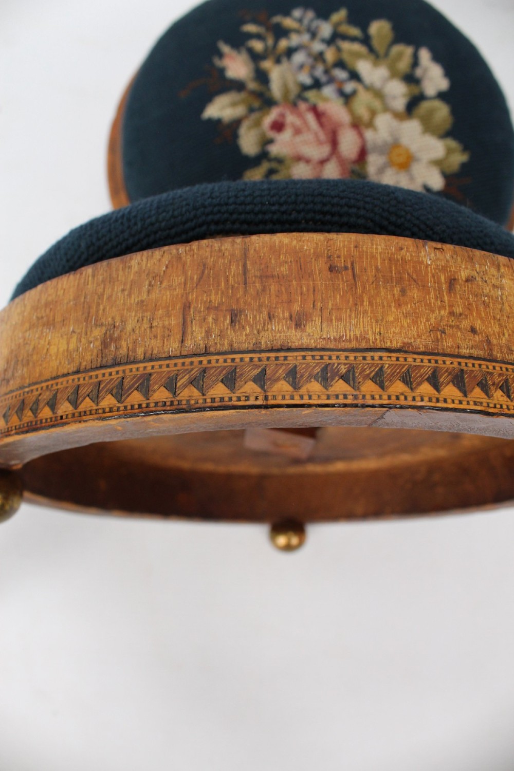 A pair of circular Early Victorian footstools featuring teal floral needlepoint tops within light wood frames and geometric mosaic borders. View VII