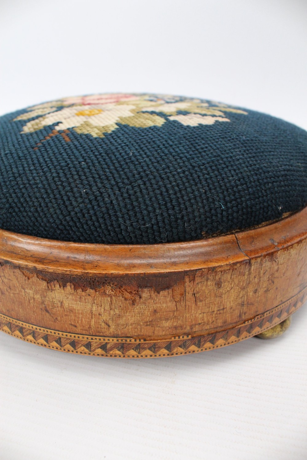 A pair of circular Early Victorian footstools featuring teal floral needlepoint tops within light wood frames and geometric mosaic borders. View XIII