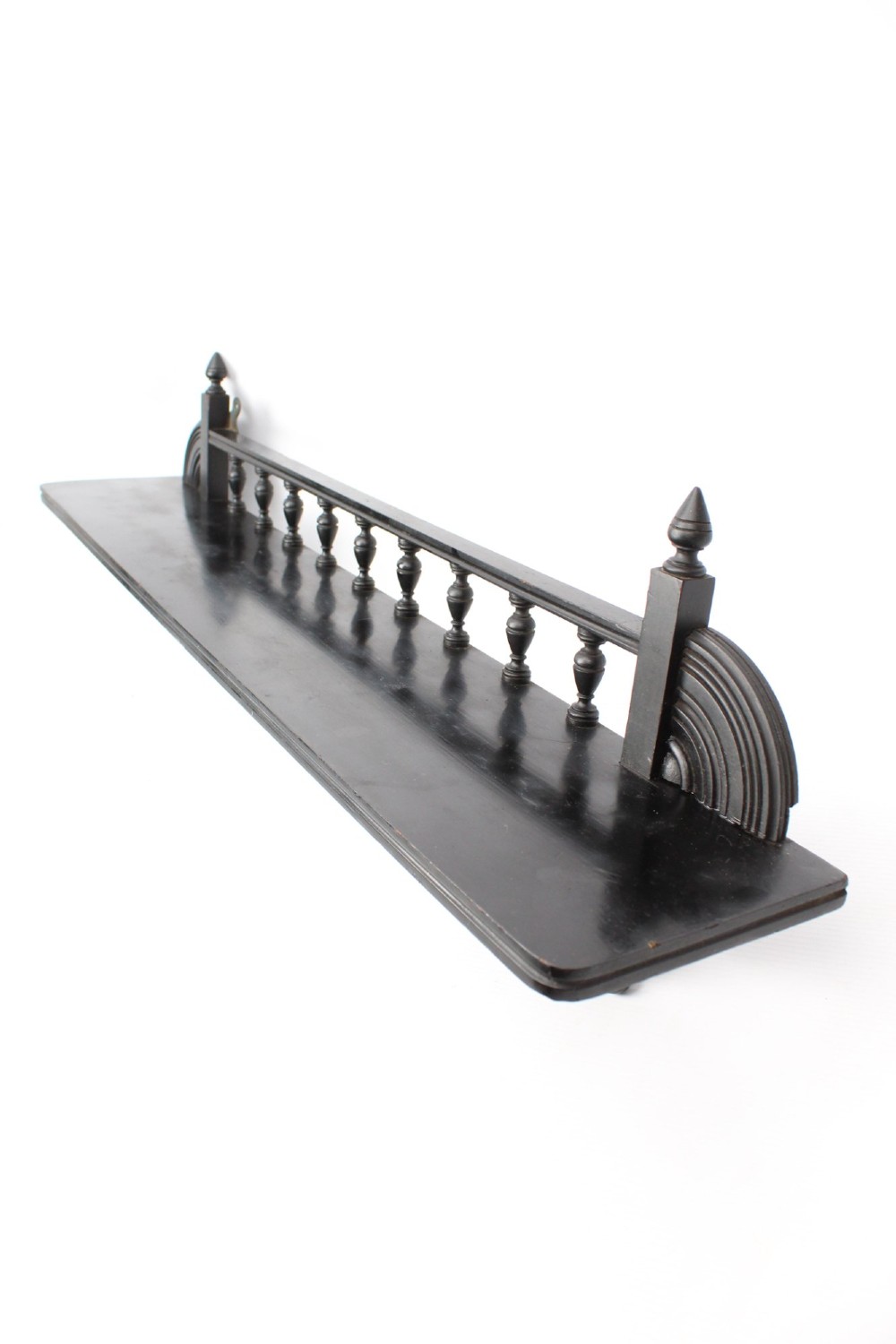 An ebonised wooden hanging wall shelf featuring a low spindle balustrade rail, turned finials, and decorative corner mouldings. View IV