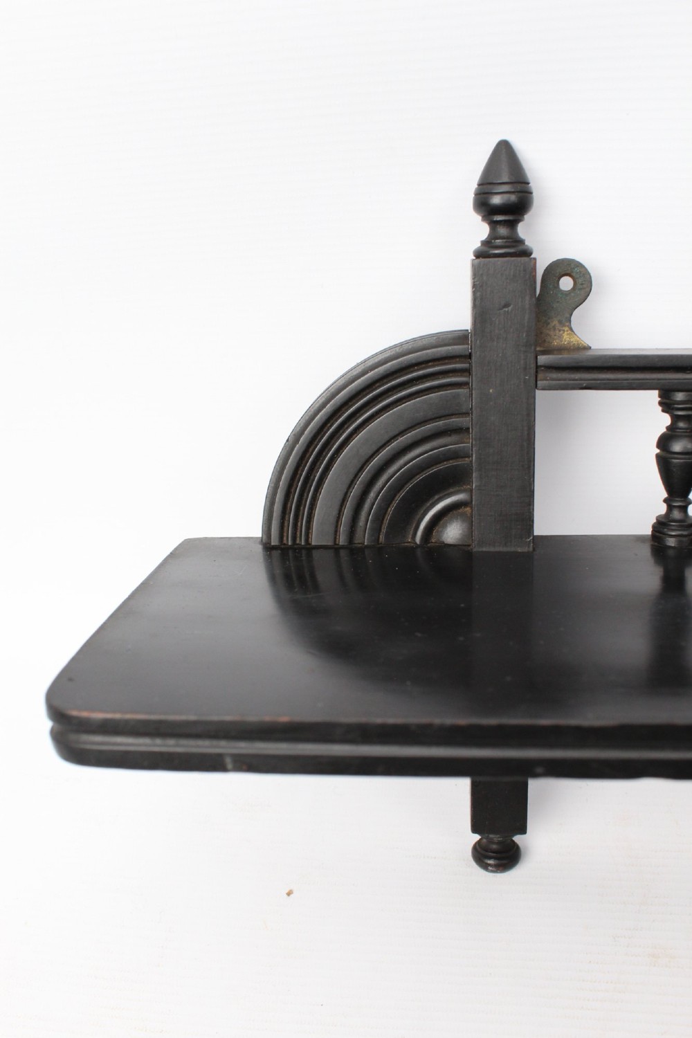 An ebonised wooden hanging wall shelf featuring a low spindle balustrade rail, turned finials, and decorative corner mouldings. View V