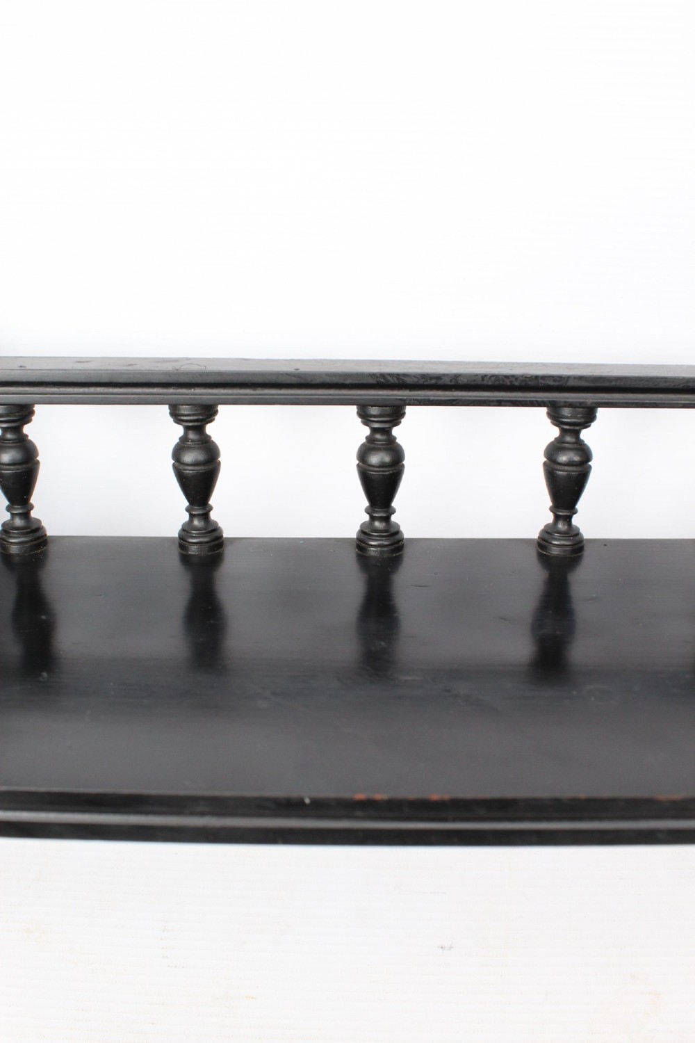 An ebonised wooden hanging wall shelf featuring a low spindle balustrade rail, turned finials, and decorative corner mouldings. View VII