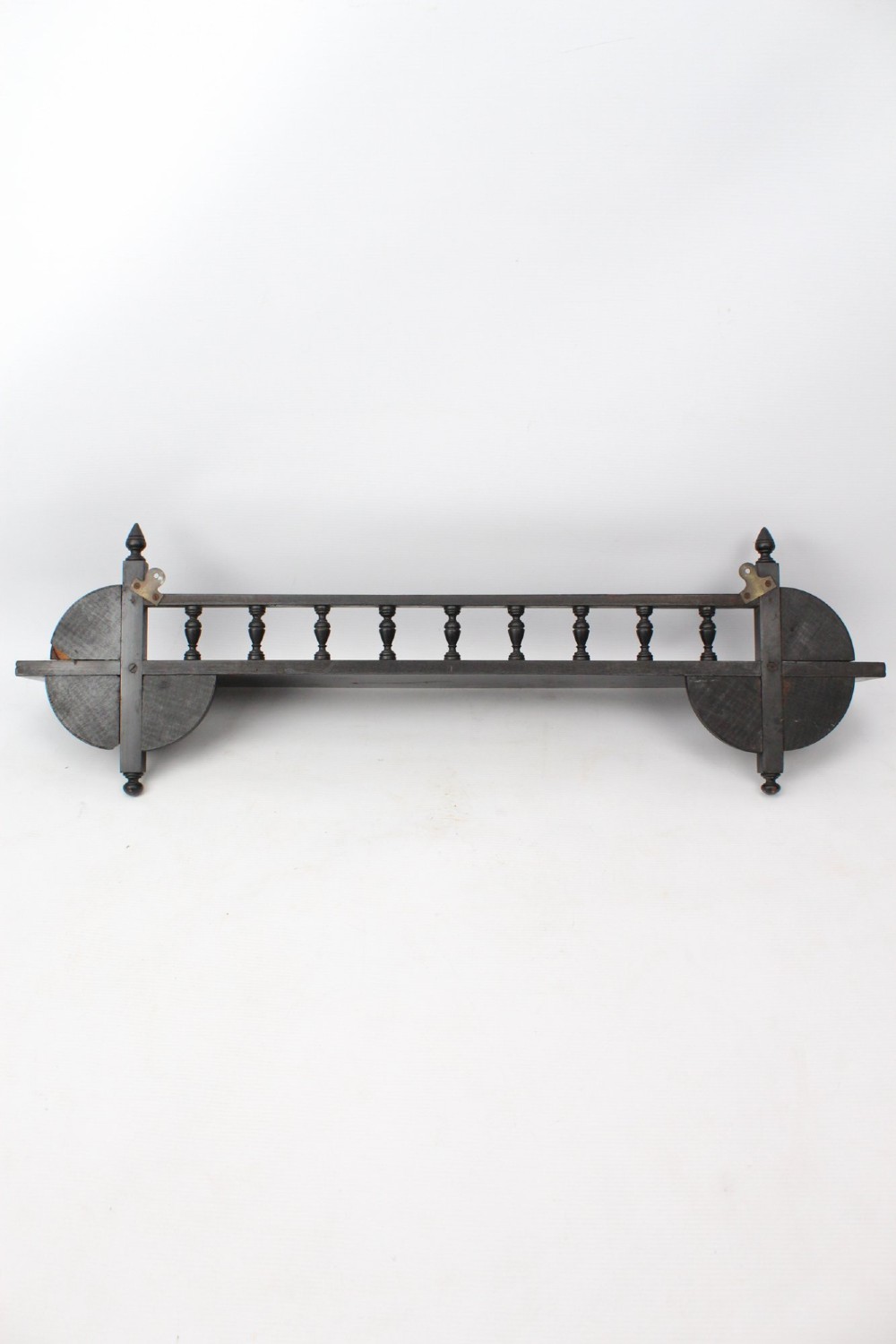 An ebonised wooden hanging wall shelf featuring a low spindle balustrade rail, turned finials, and decorative corner mouldings. View IX