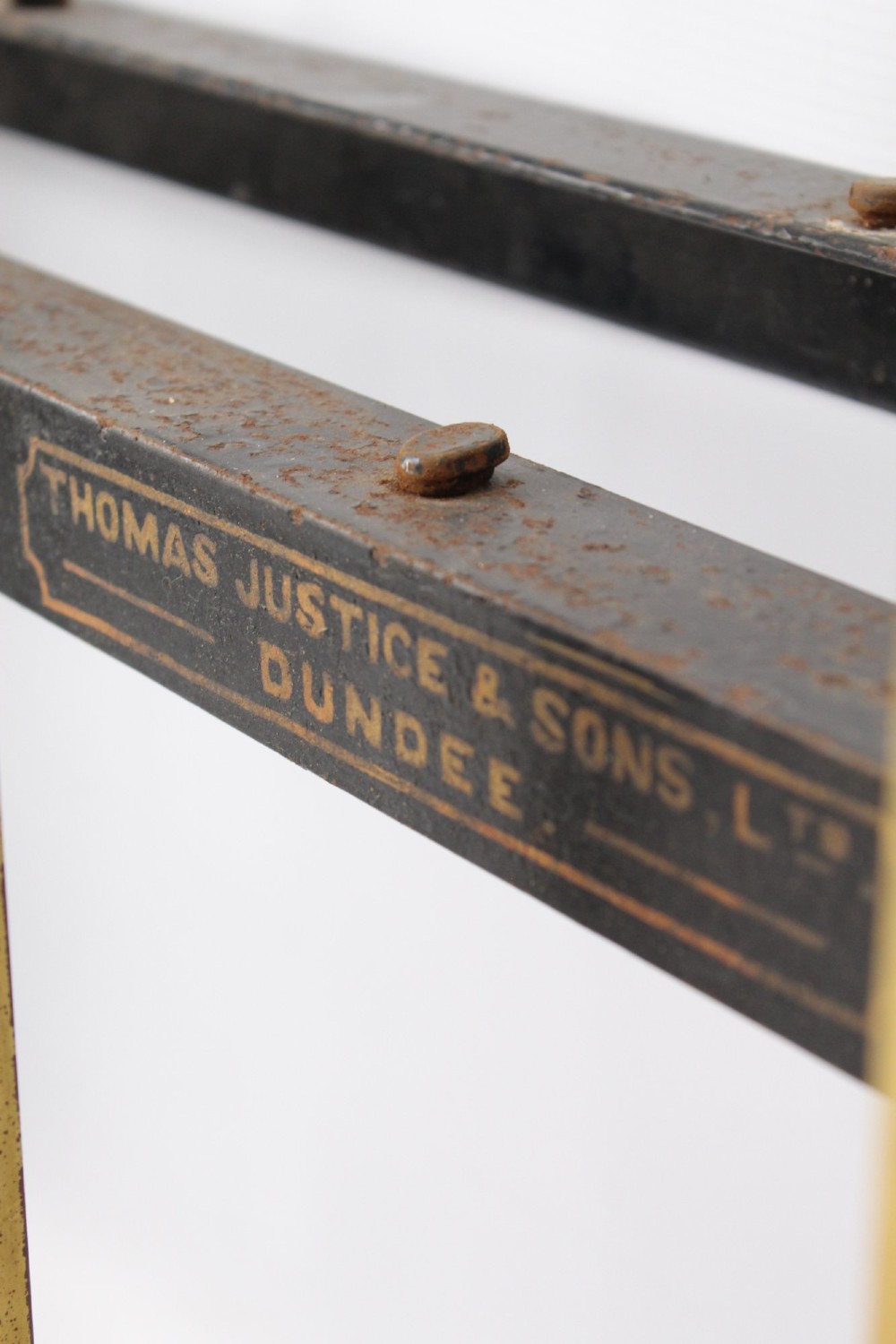 A Victorian brass single bed frame featuring a gently curved top rail, vertical spindles, turned finials, and original wheel castors. View VII